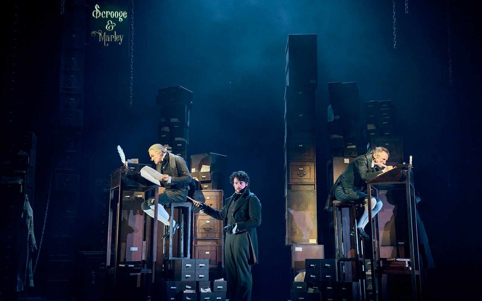Stage scene from "A Christmas Carol - A Ghost Story" with actors in Victorian attire.