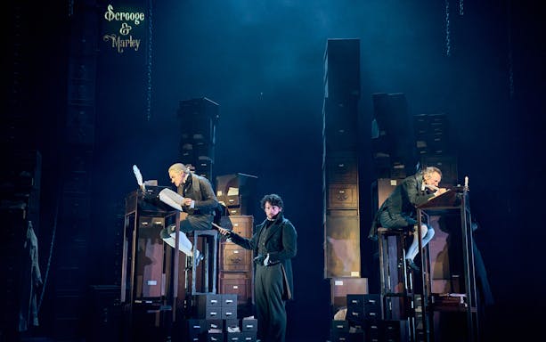 Stage scene from "A Christmas Carol - A Ghost Story" with actors in Victorian attire.