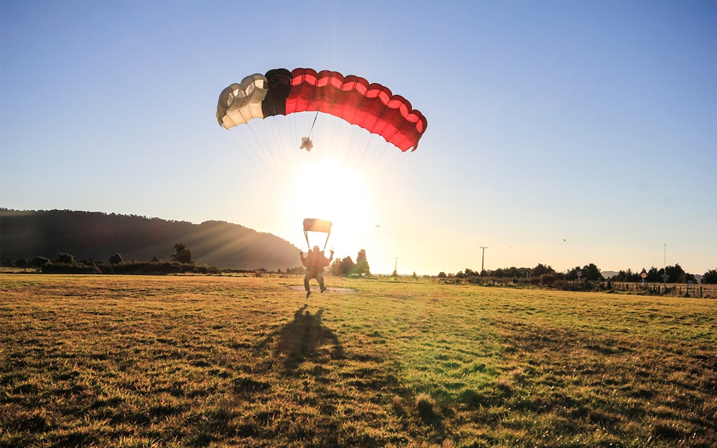 Skydiver landing at sunset in Franz Josef, New Zealand.