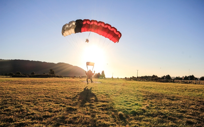 Skydiver landing at sunset in Franz Josef, New Zealand.