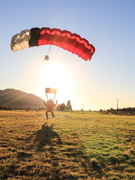 Skydiver landing at sunset in Franz Josef, New Zealand.
