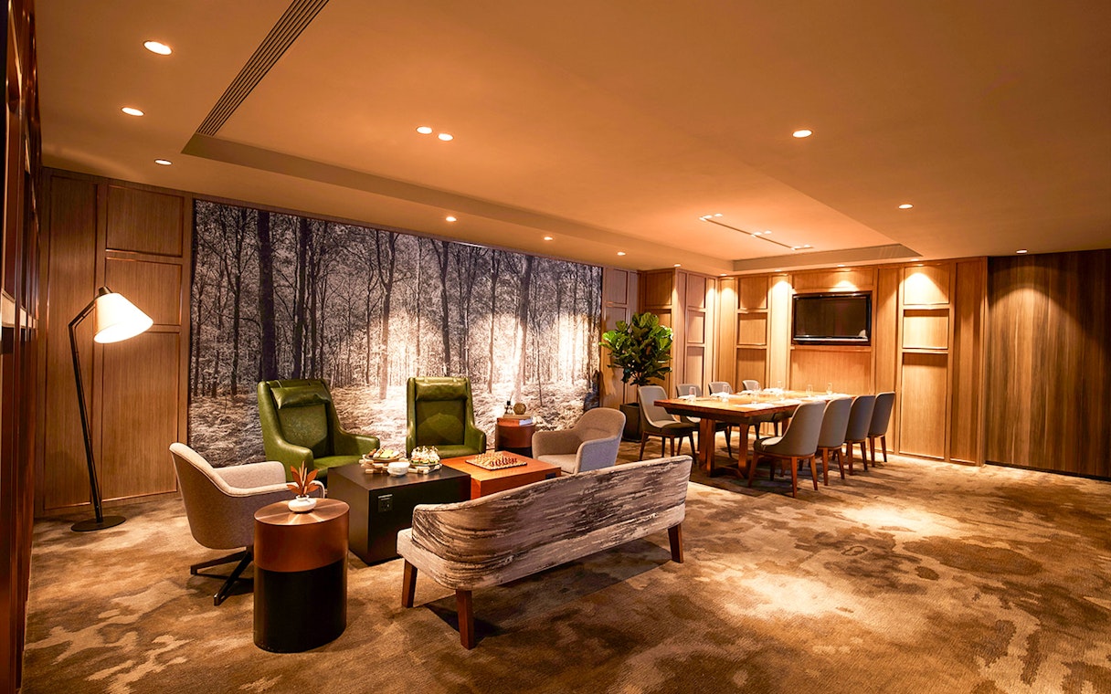 First-class lounge seating area at Hong Kong International Airport with dining table and chairs.