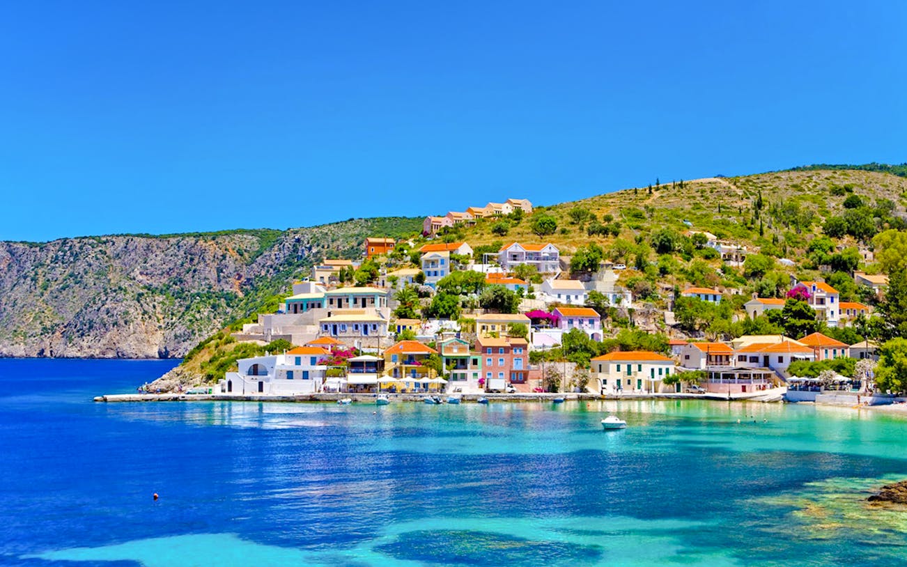 Colorful houses on the hillside of Assos Village, Kefalonia island, Greece, overlooking the turquoise sea.