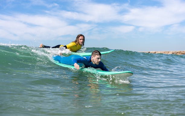 Surfers learning to ride waves during a lesson in Costa da Caparica.