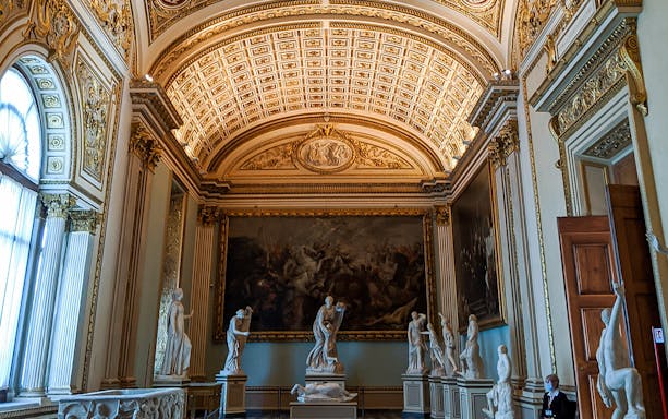 Ornate museum hall with classical sculptures and large painting, Combo Entrance Ticket with Host.