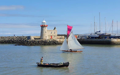 Sailboat and fishing boat near Howth Harbour lighthouse, Dublin.