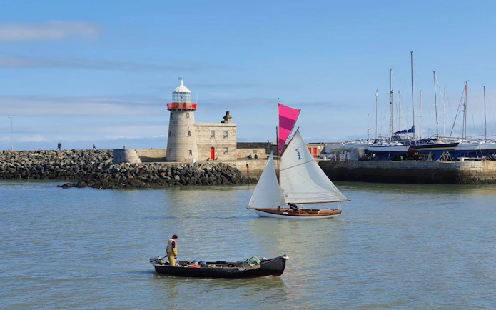 Sailboat and fishing boat near Howth Harbour lighthouse, Dublin.
