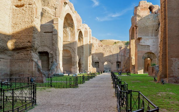 Ancient ruins of the Baths of Caracalla in Rome, showcasing large arches and stone pathways.
