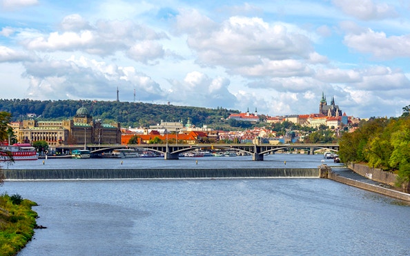 River cruise view of Prague with historic buildings and bridges.