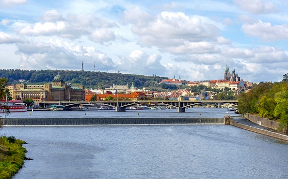 River cruise view of Prague with historic buildings and bridges.