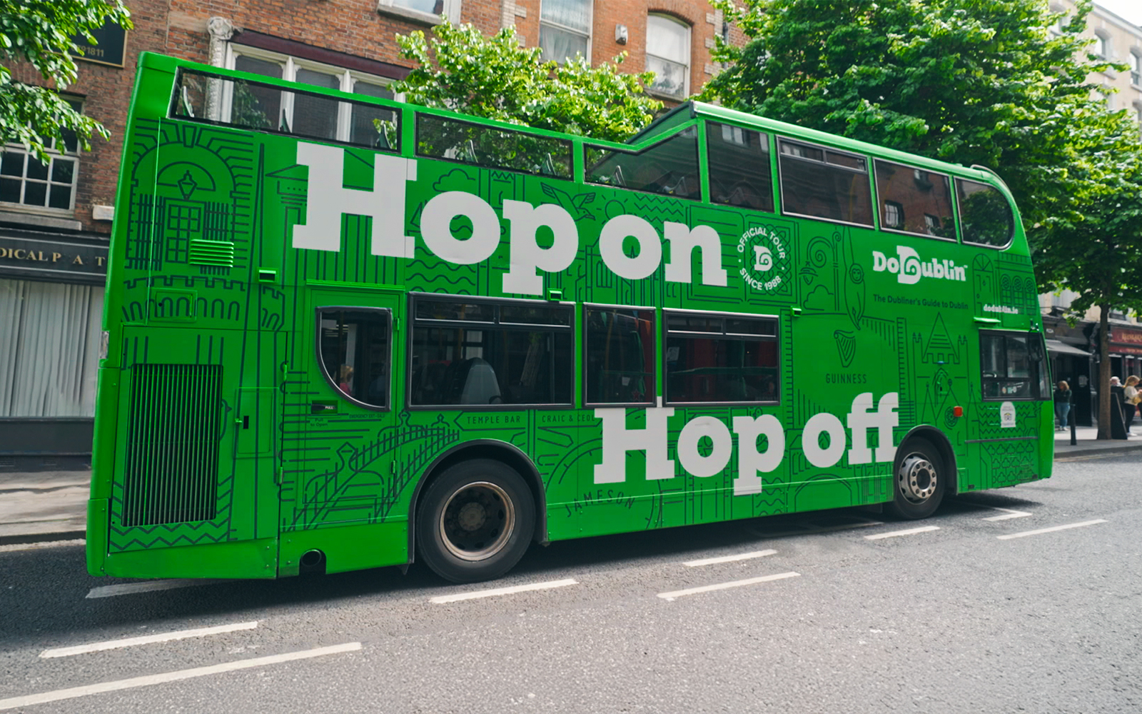 Dublin green hop-on hop-off tour bus on city street.