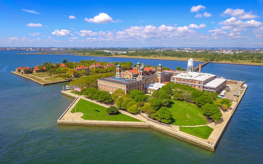 Aerial view of Ellis Island in New York Harbor with historic buildings and green spaces.