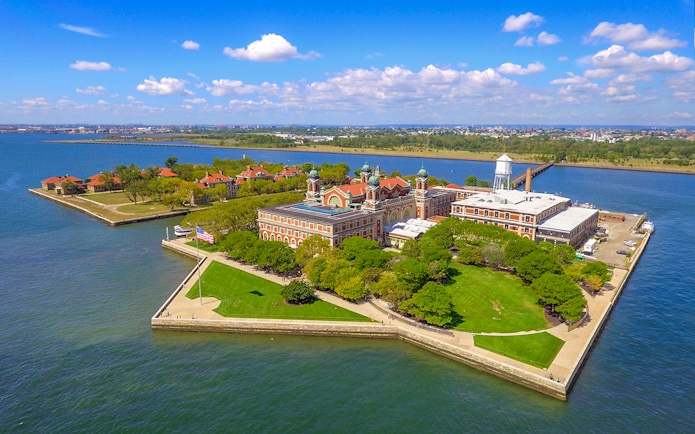 Aerial view of Ellis Island in New York Harbor with historic buildings and green spaces.