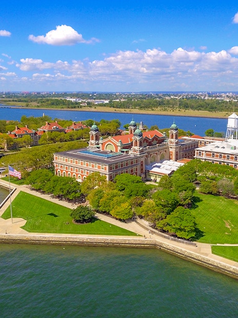 Aerial view of Ellis Island in New York Harbor with historic buildings and green spaces.