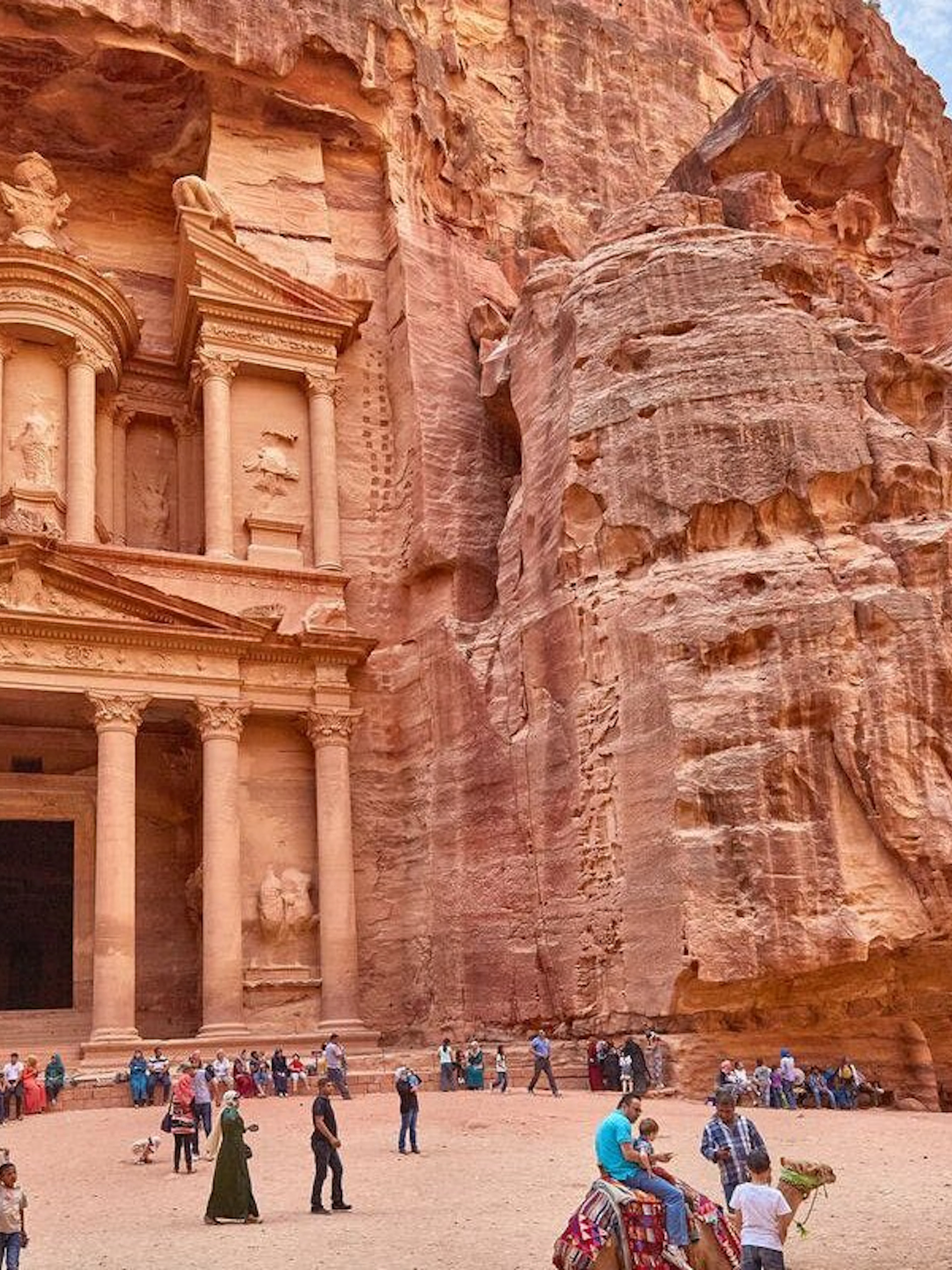 Petra's Al-Khazneh with tourists exploring the ancient site in Jordan.