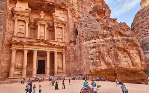 Petra's Al-Khazneh with tourists exploring the ancient site in Jordan.