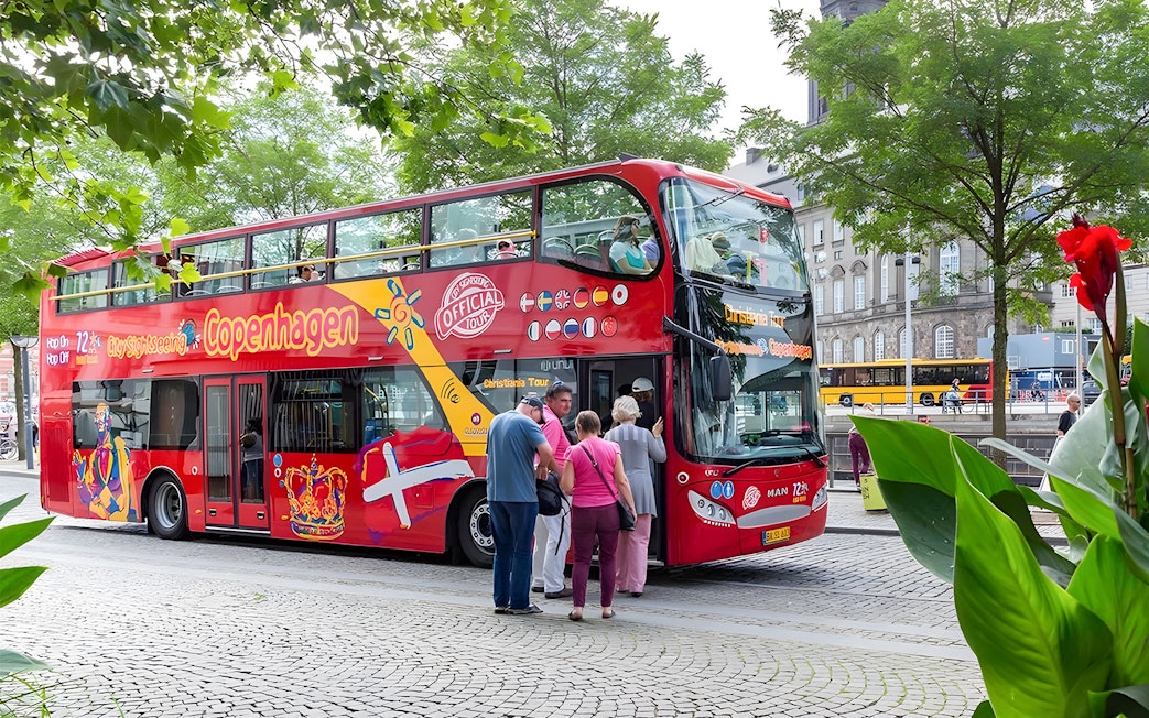 Tourists boarding a red hop-on hop-off bus in Copenhagen.