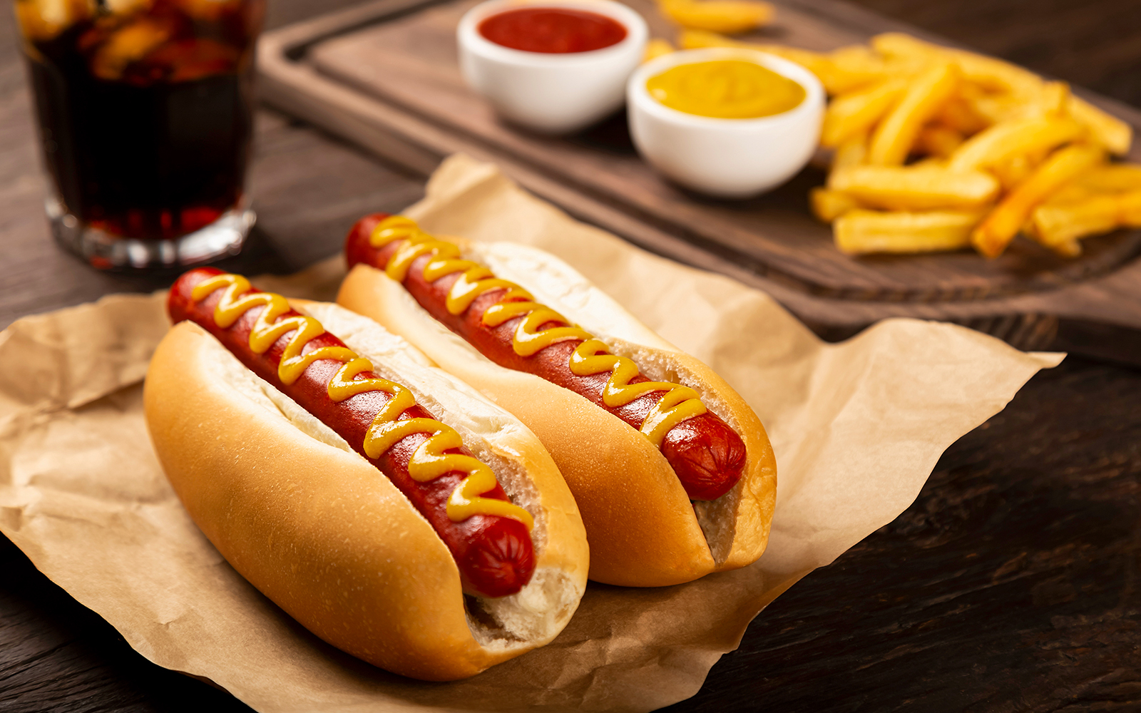 Hot dogs with mustard and ketchup, served with french fries and soda.