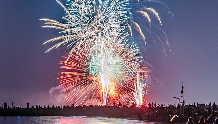 People celebrating Ferragosto festival with fireworks in the night sky, Italy.
