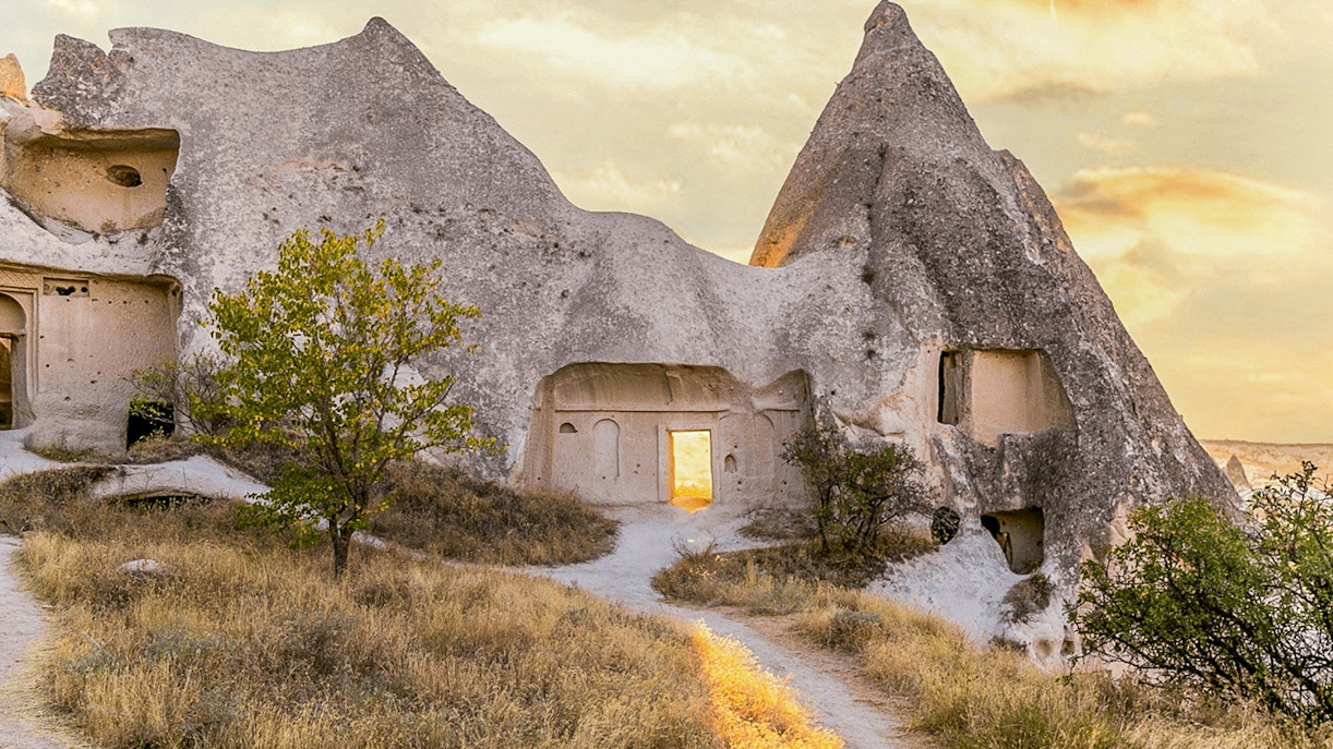 Cappadocia rock formations with ancient cave dwellings at sunset.