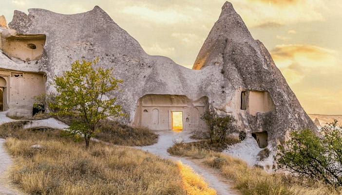 Cappadocia rock formations with ancient cave dwellings at sunset.