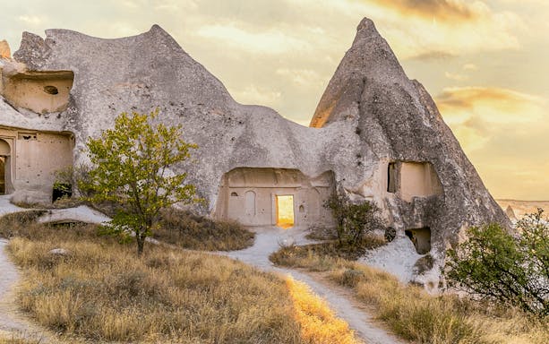 Cappadocia rock formations with ancient cave dwellings at sunset.