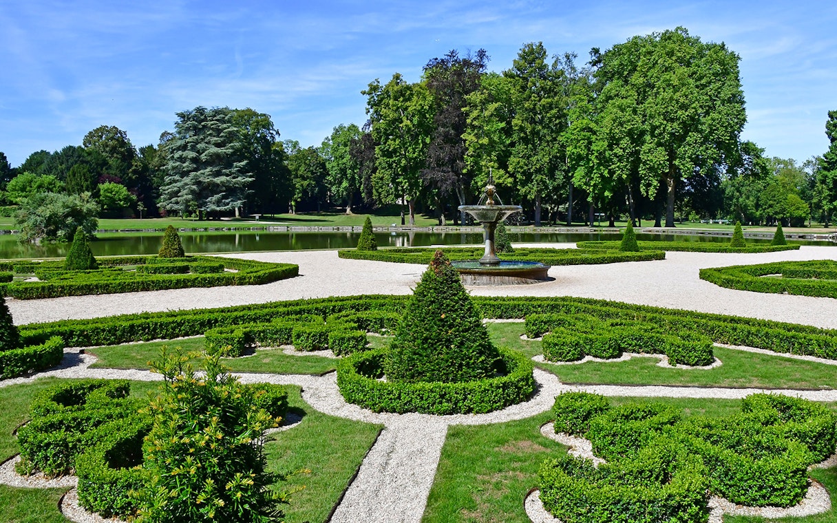 Fountain and manicured hedges in the Garden of Castle Chantilly, France.