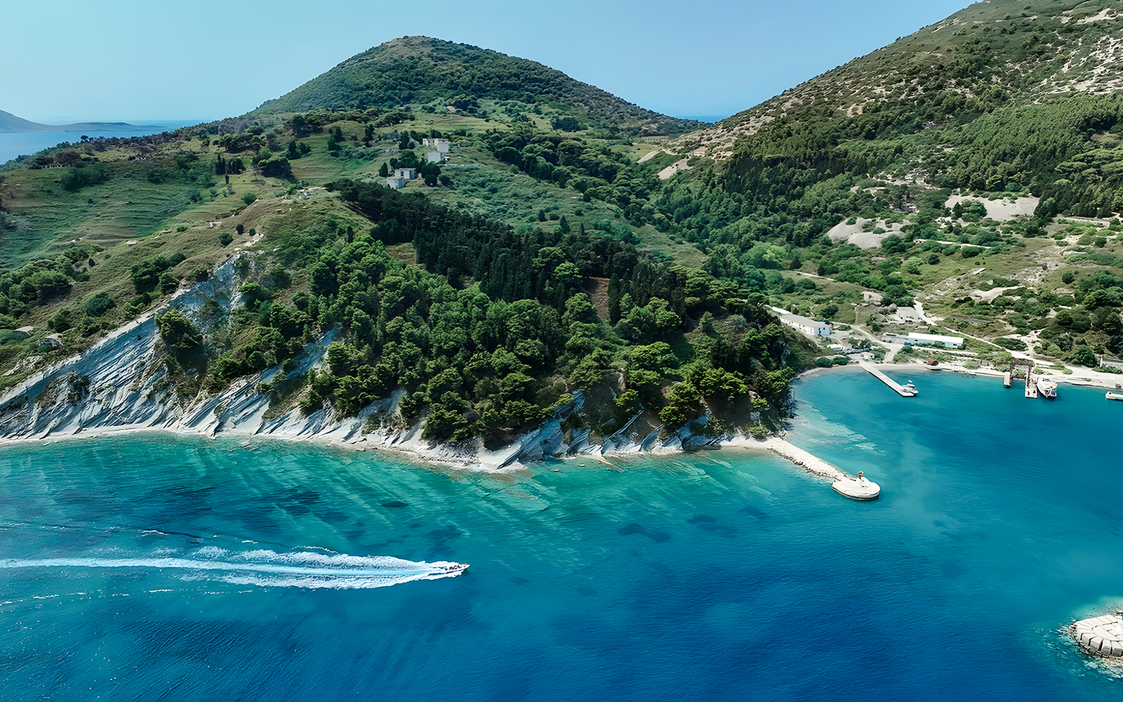Aerial view of Vlora coastline with a pirate boat tour in Albania's Ionian Sea.
