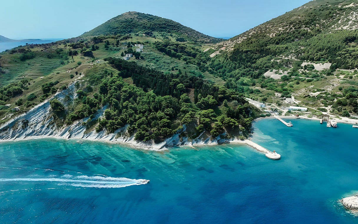 Aerial view of Vlora coastline with a pirate boat tour in Albania's Ionian Sea.