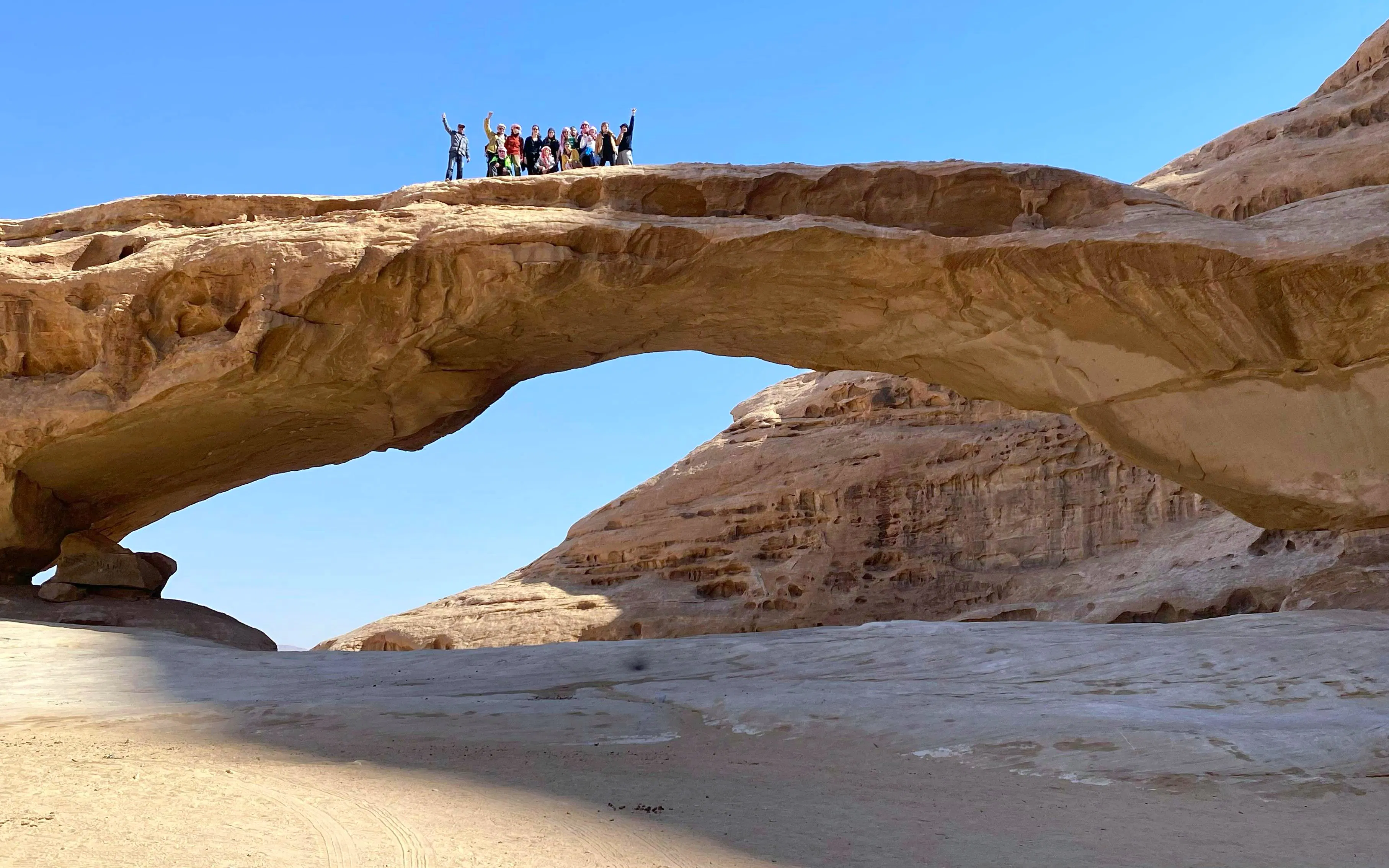 Group on rock bridge in Wadi Rum desert during Amman to Petra tour.