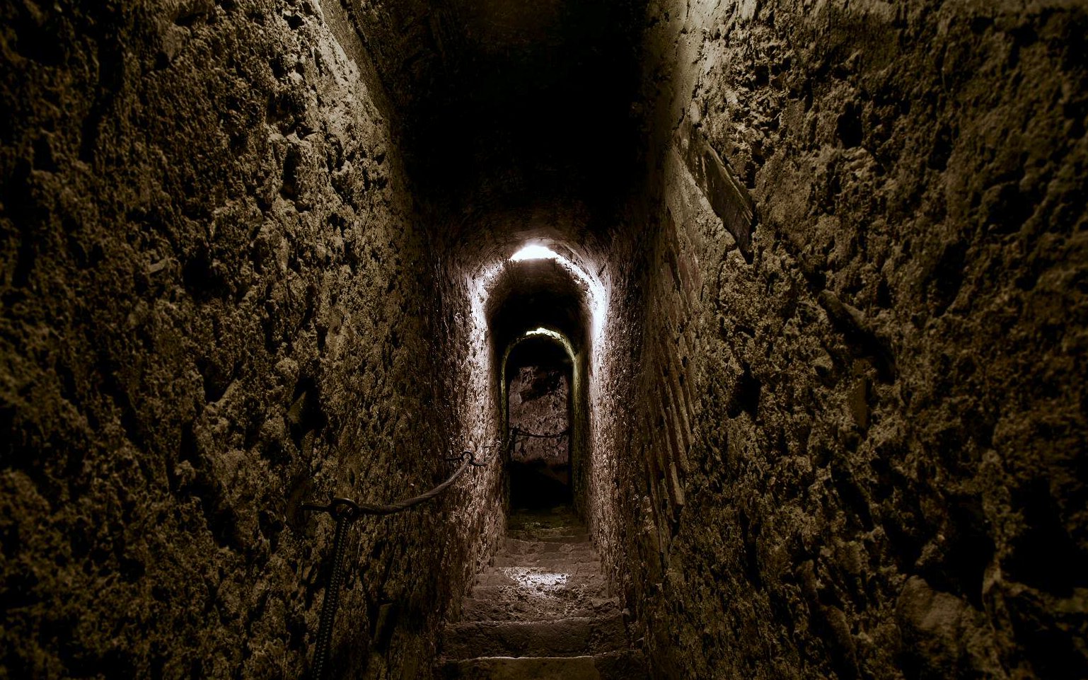 Bran Castle secret passageway with stone walls and dim lighting.