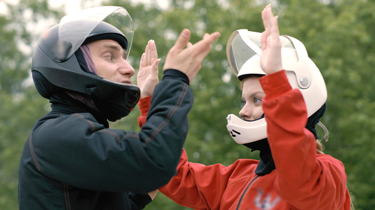 Trainer instructing woman skydiver with helmets before flight.