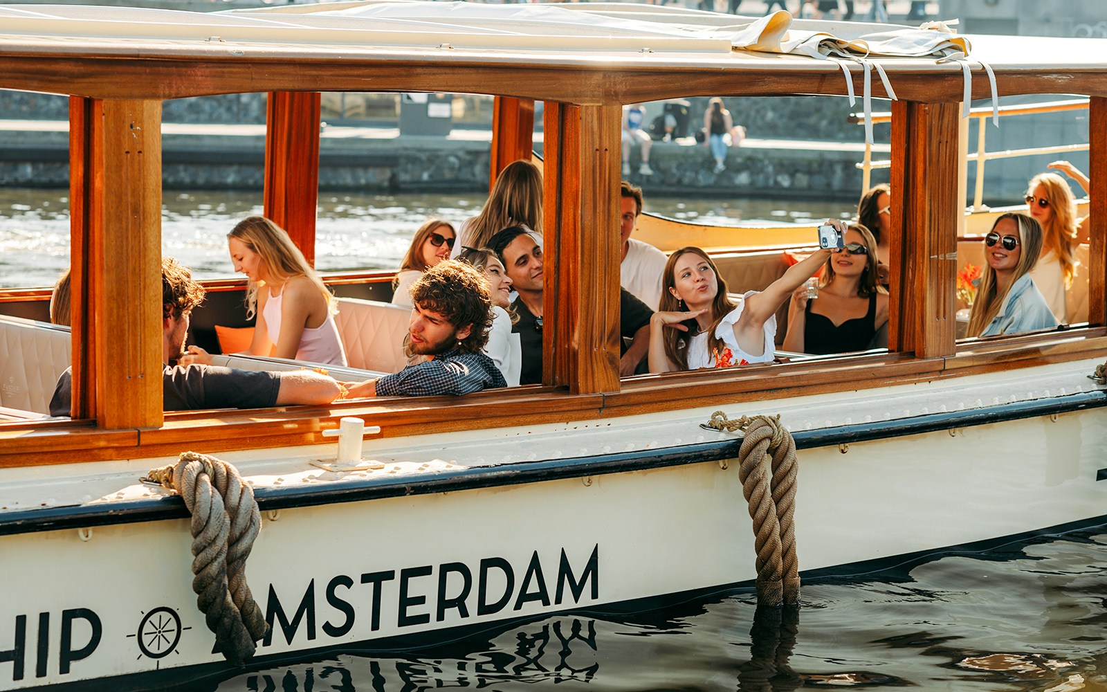 Guests enjoying an evening canal cruise in Amsterdam with illuminated cityscape views.