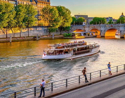 Seine River cruise boat passing by the Eiffel Tower in Paris, France.