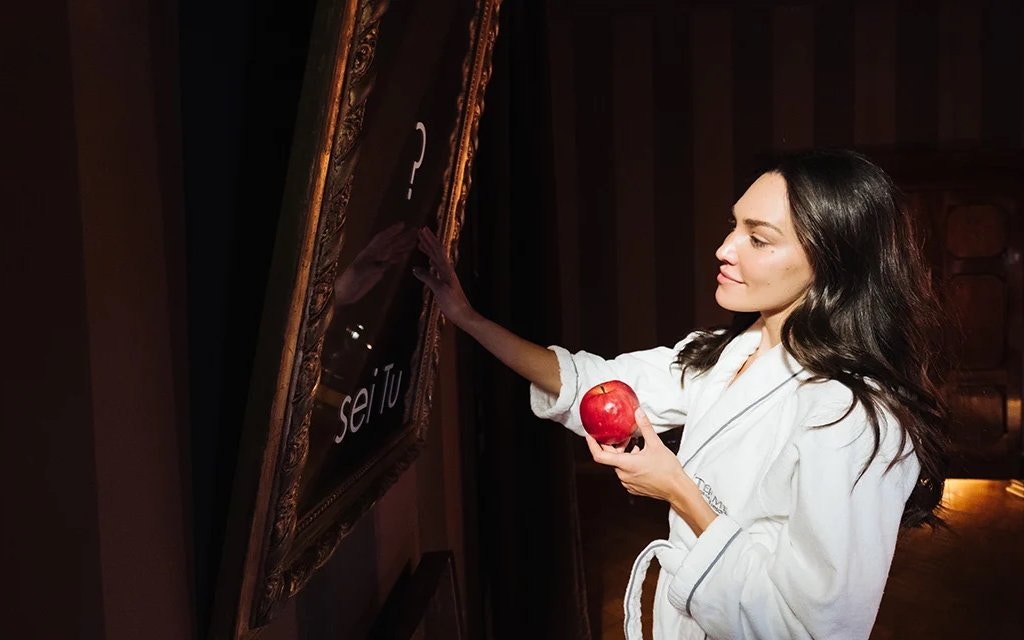 Woman in a robe holding an apple at QC Terme Torino spa.