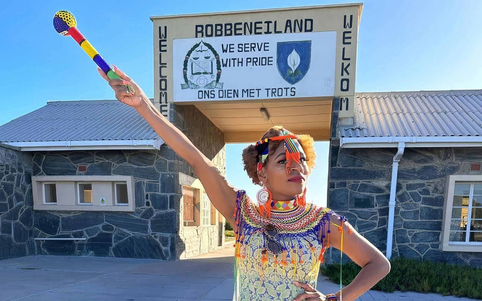 Guide in traditional attire at Robben Island prison entrance, South Africa.