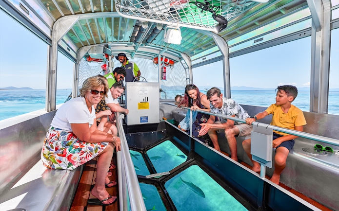 Tourists enjoying a glass bottom boat ride from Cairns to Green Island, viewing marine life.