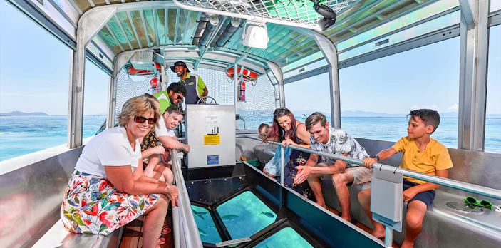 Tourists enjoying a glass bottom boat ride from Cairns to Green Island, viewing marine life.