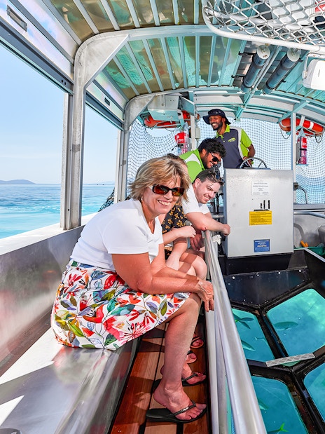 Tourists enjoying a glass bottom boat ride from Cairns to Green Island, viewing marine life.
