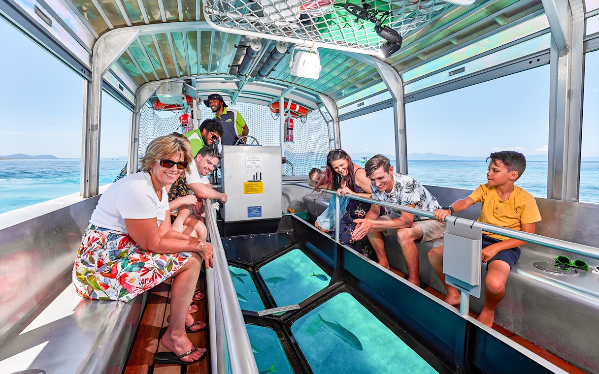 Tourists enjoying a glass bottom boat ride from Cairns to Green Island, viewing marine life.