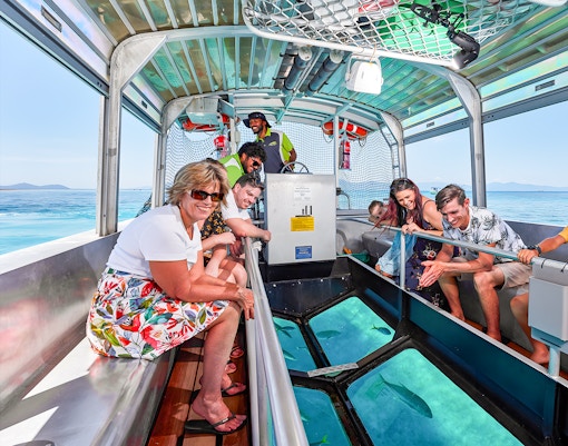 Tourists enjoying a glass bottom boat ride from Cairns to Green Island, viewing marine life.