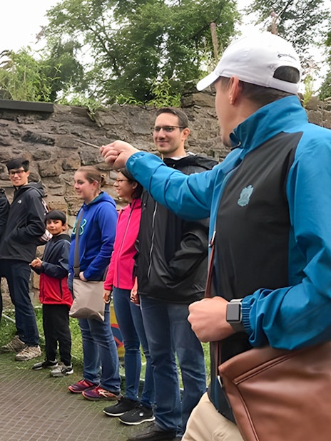 Group on Harry Potter walking tour with guide demonstrating wand technique.