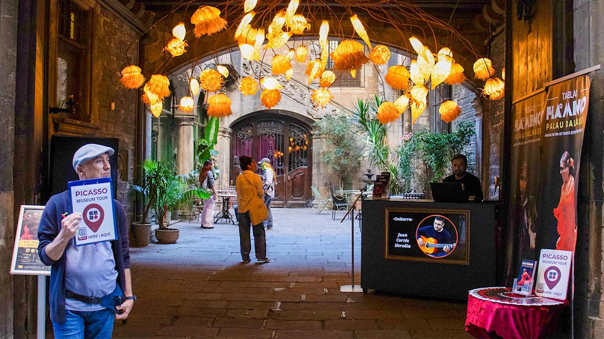 Picasso Museum entrance with tour guide and decorative lights in Barcelona courtyard.