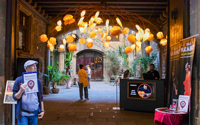 Picasso Museum entrance with tour guide and decorative lights in Barcelona courtyard.