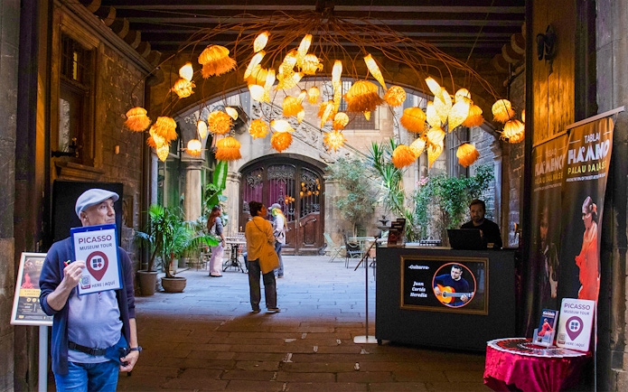 Picasso Museum entrance with tour guide and decorative lights in Barcelona courtyard.