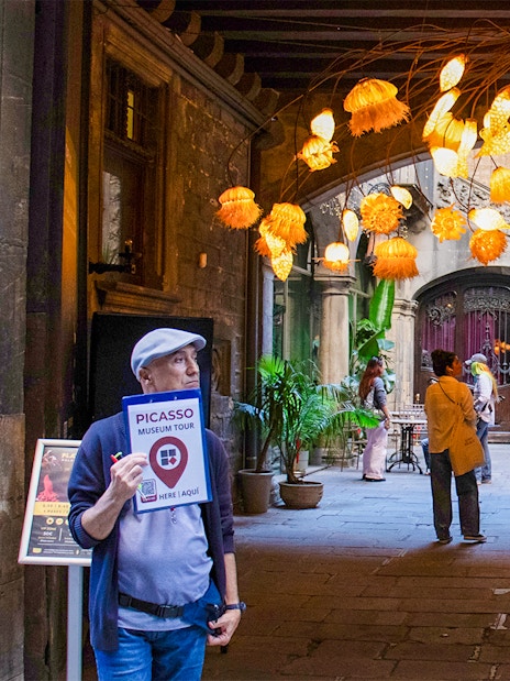 Picasso Museum entrance with tour guide and decorative lights in Barcelona courtyard.