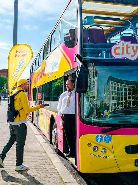 Guests boarding City Circle Bus in Berlin near historic building.