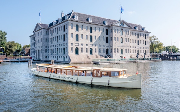 Canal boat cruising past the National Maritime Museum in Amsterdam.