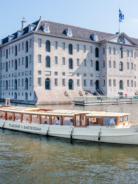 Canal boat cruising past the National Maritime Museum in Amsterdam.