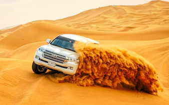 SUV driving through sand dunes on a Dubai Red Dunes Desert Safari.